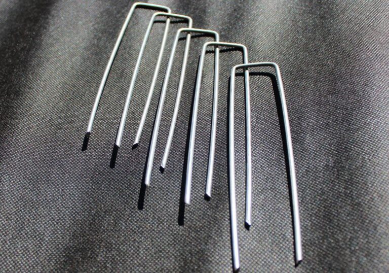 Silver metal U-stakes for securing landscape fabric or garden netting.