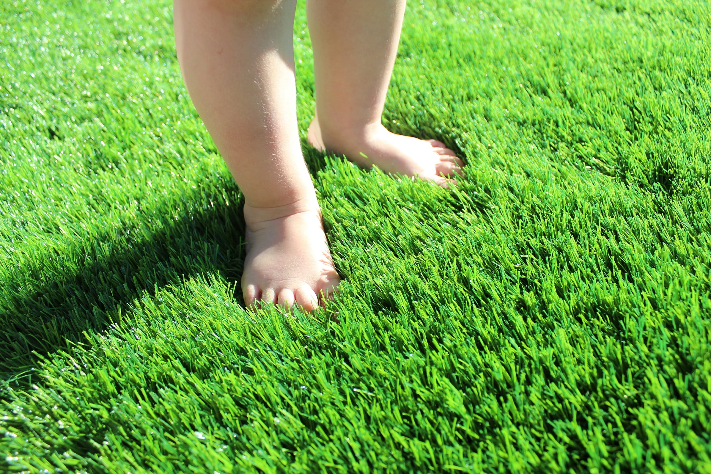 Premium Grass Blades Synthetic Artificial Turf: Baby Standing in Soft Lush turf