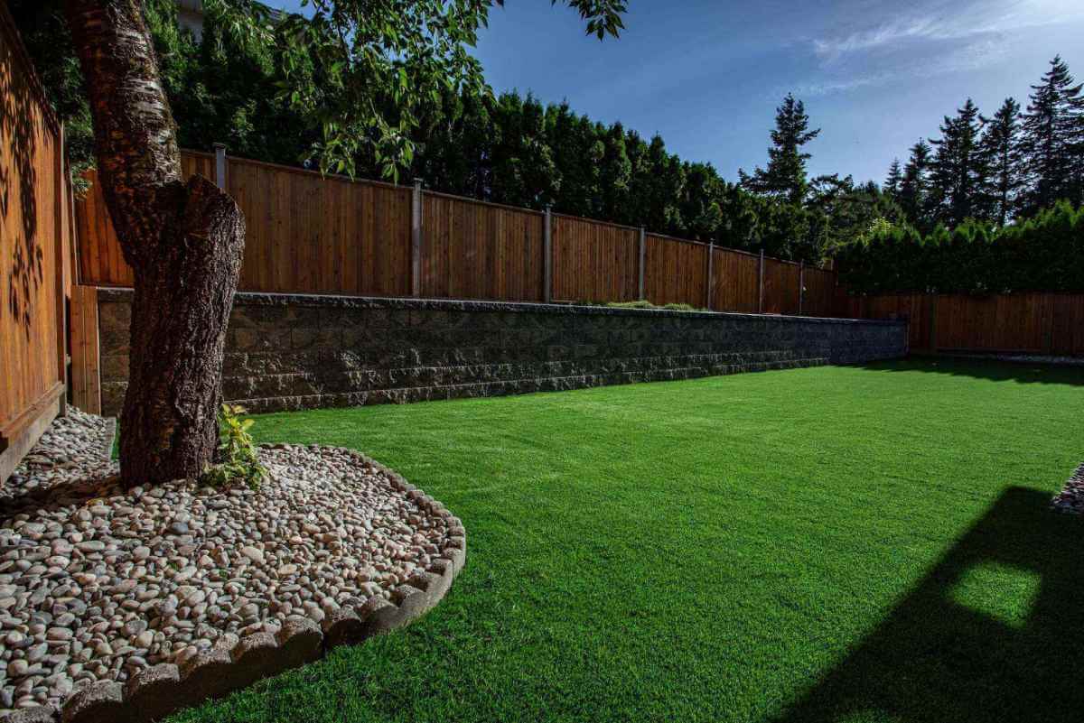 Premium Grass Blades Synthetic Artificial Turf: Lush Turf beside new retaining wall contoured with riverrock
